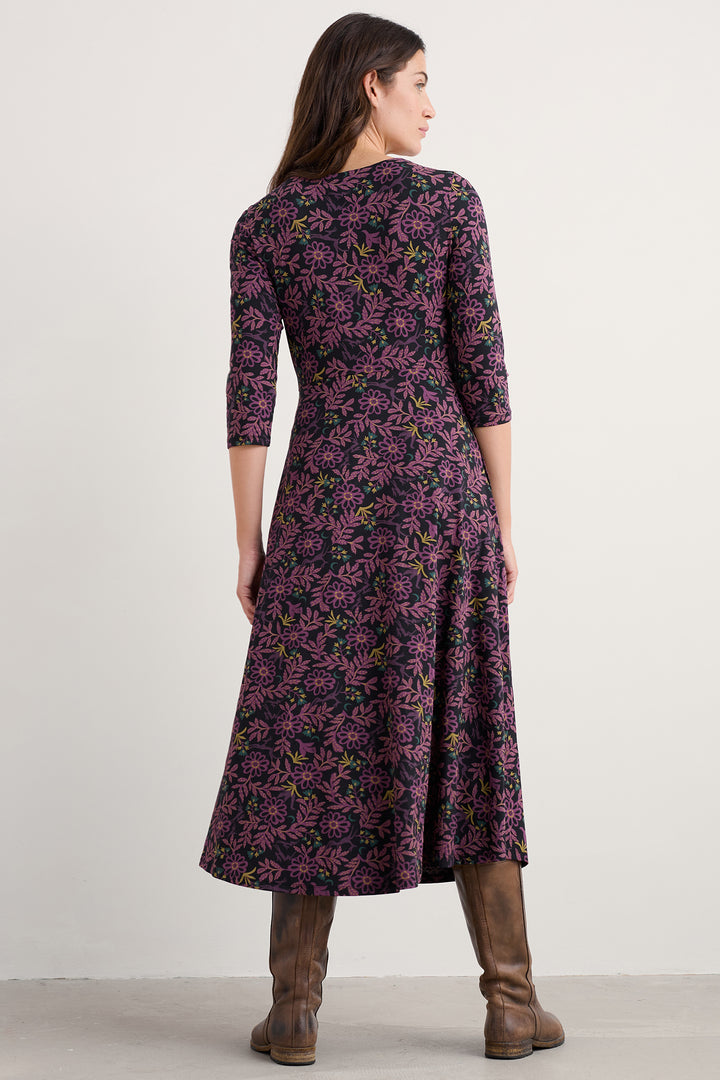 Woman wearing a purple floral dress on a plain background