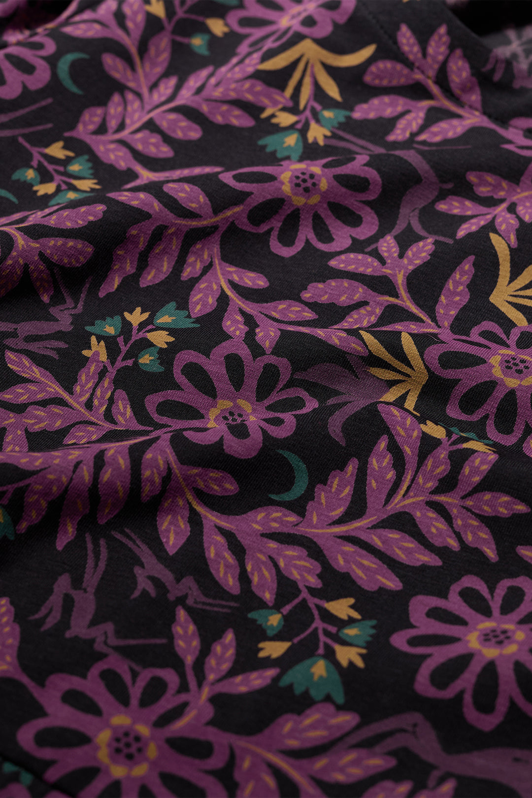 Close-up of floral fabric with purple flowers and green leaves on a black background