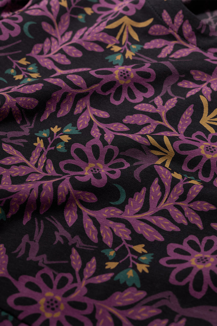 Close-up of floral fabric with purple flowers and green leaves on a black background