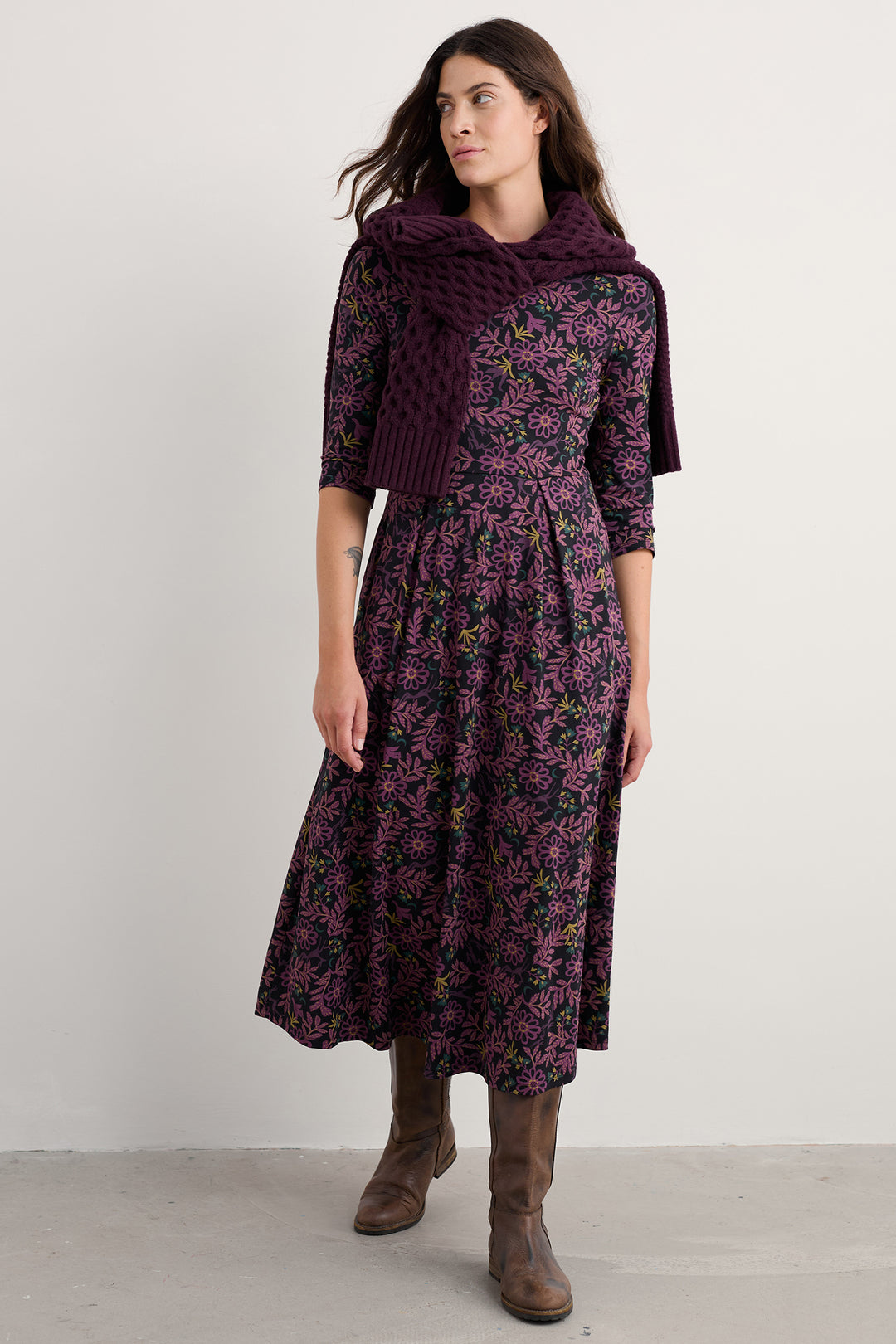 Woman wearing a dark floral dress with a matching scarf against a white background