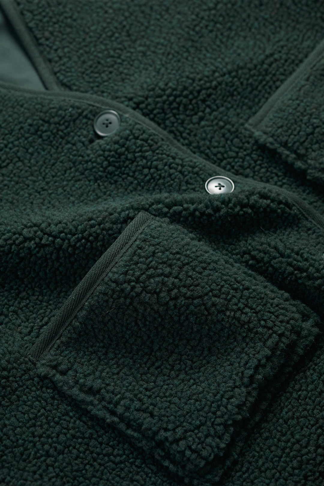 Close-up of a dark green fleece jacket with buttons and pocket details.
