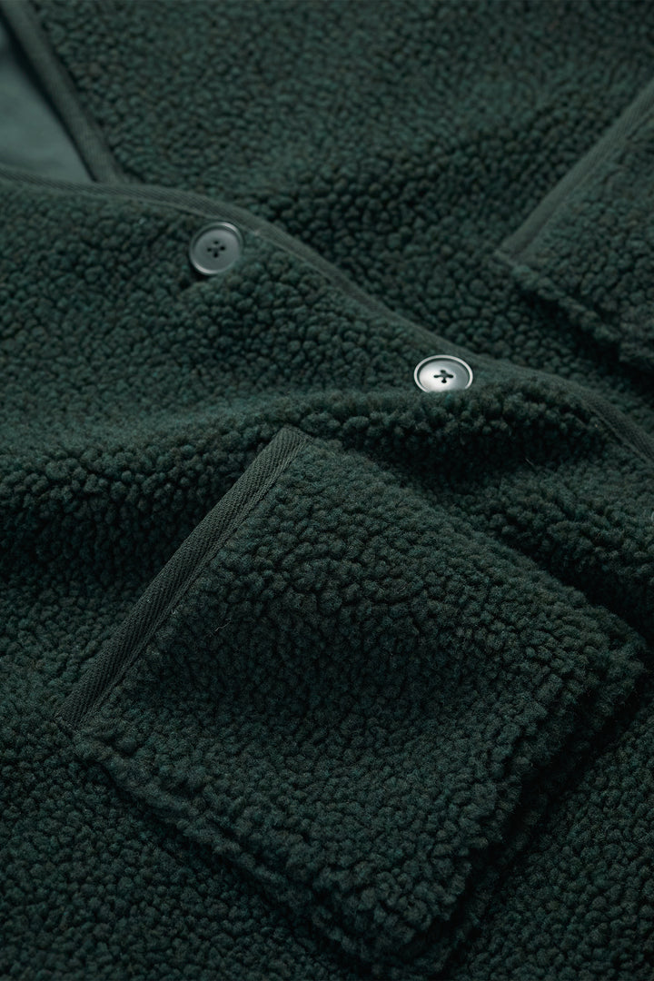 Close-up of a dark green fleece jacket with buttons and pocket details.