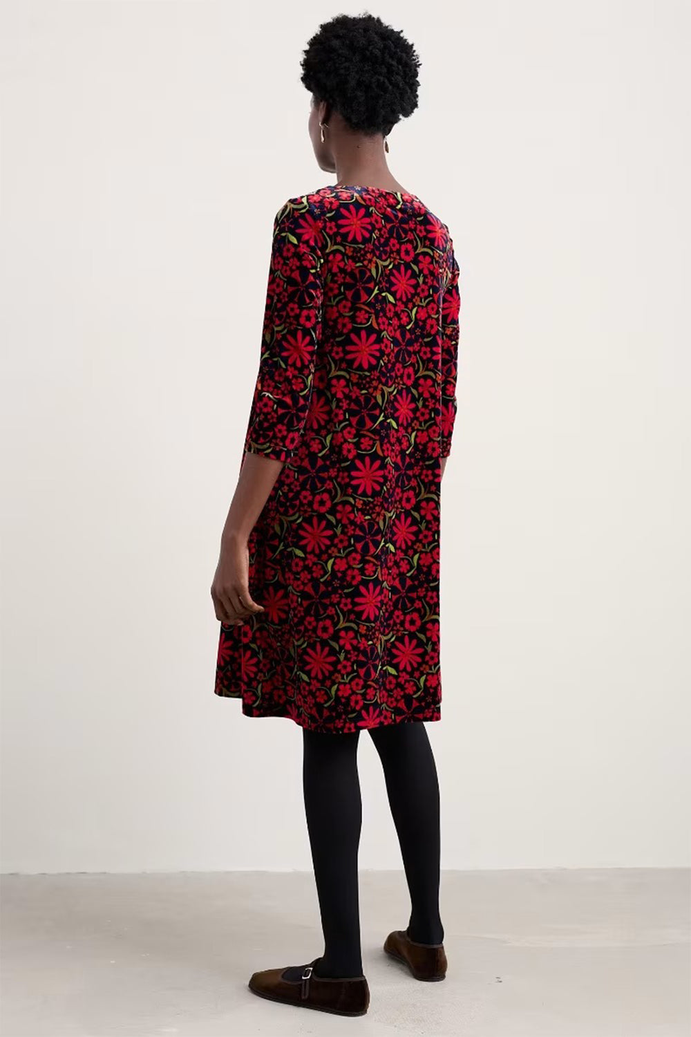 Person wearing a red floral dress against a white background
