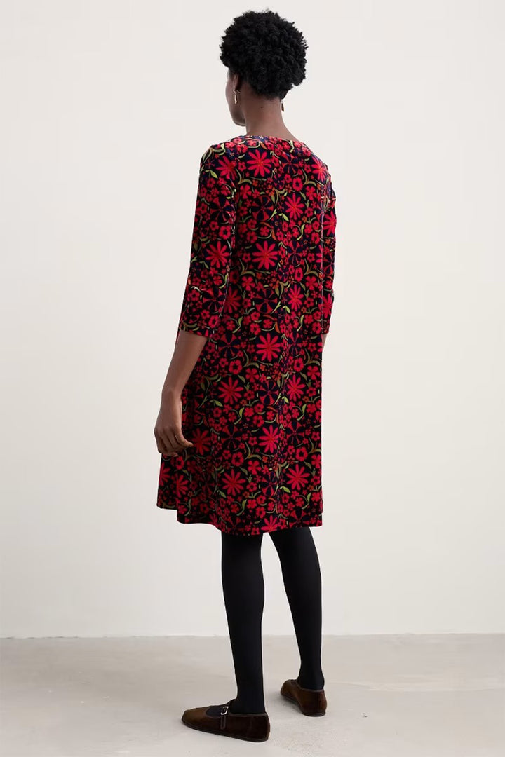 Person wearing a red floral dress against a white background