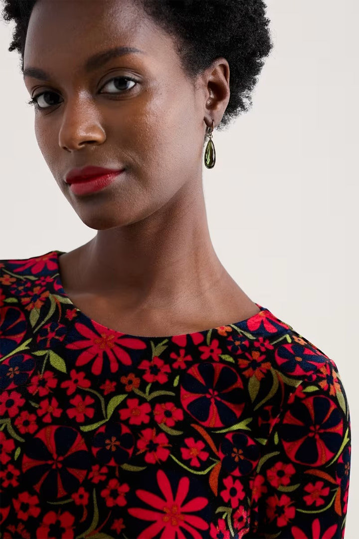 Woman wearing a colorful floral dress with a neutral background
