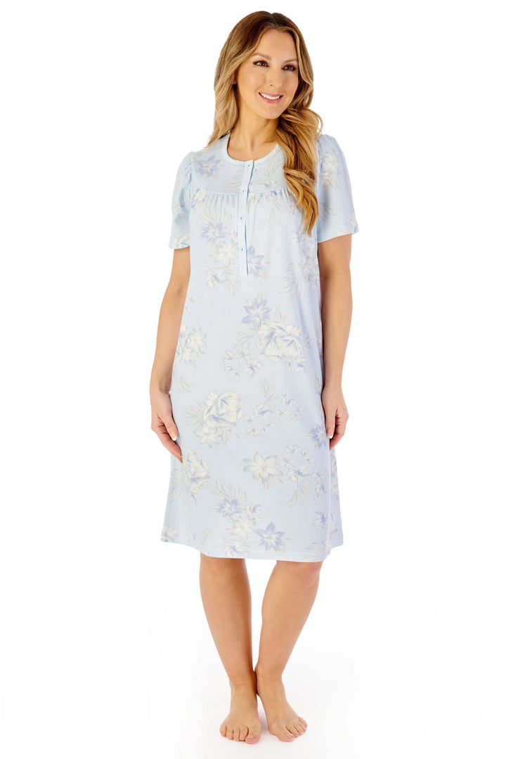 Woman wearing a light blue floral nightgown on a white background
