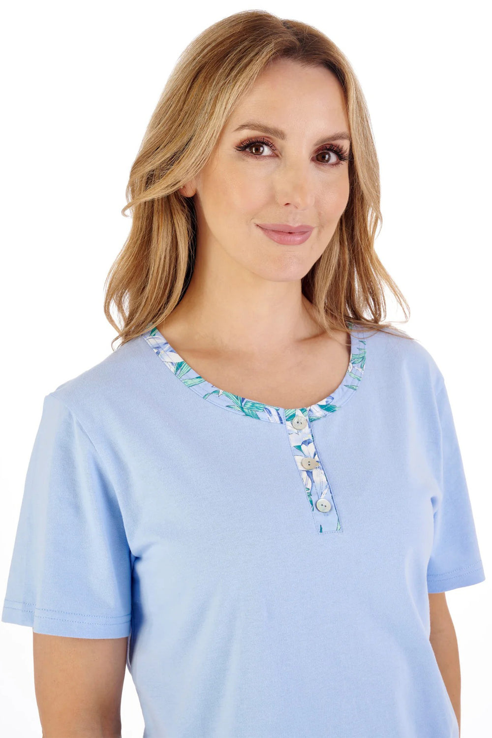 Woman wearing a light blue top with floral embroidery on a white background