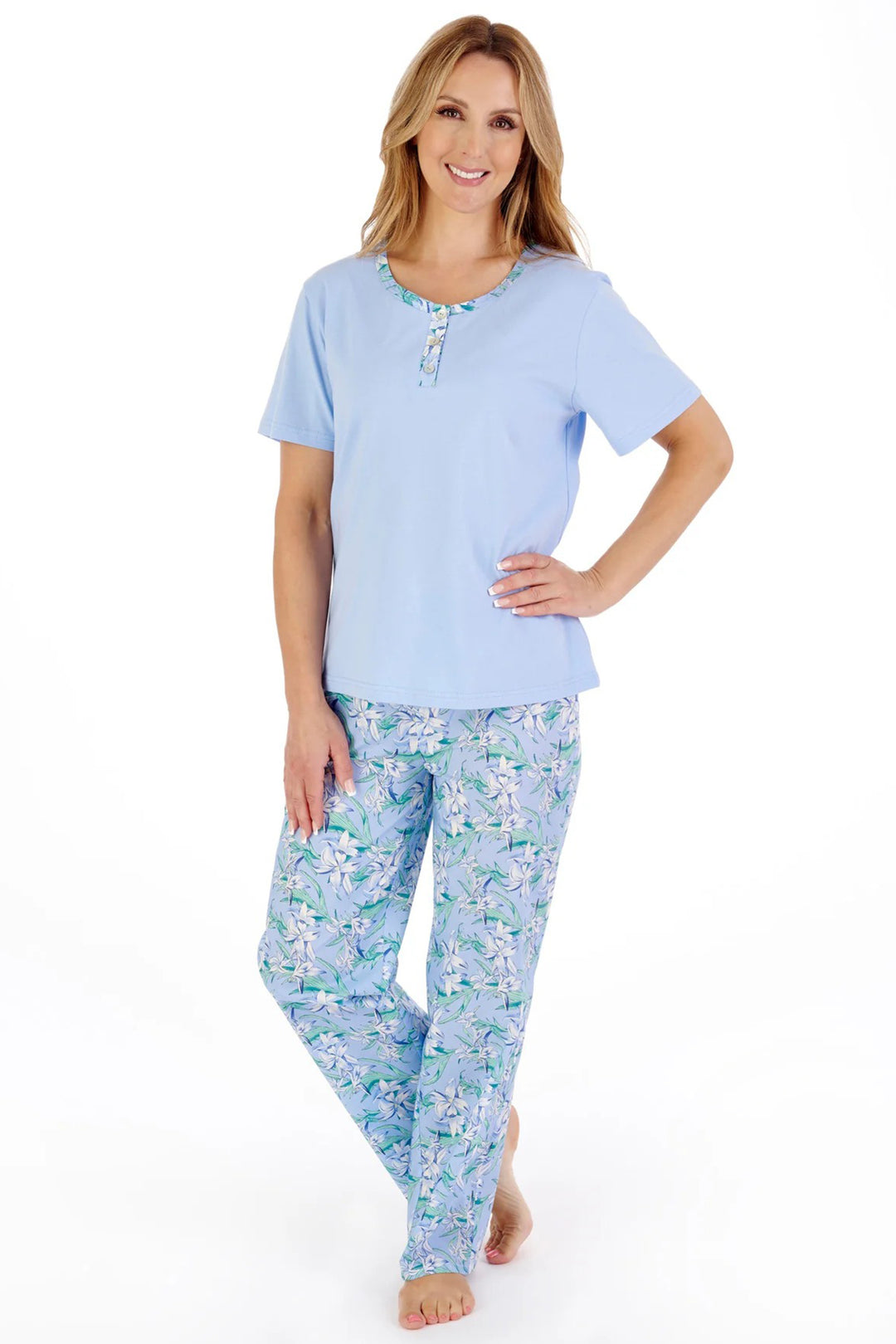 Woman wearing a light blue pajama set with floral pants on a white background