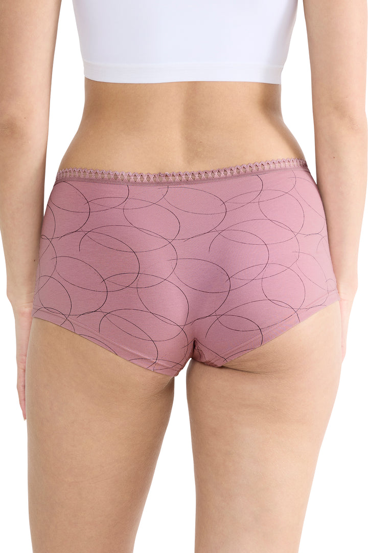 Person wearing pink patterned underwear with a white top on a plain background