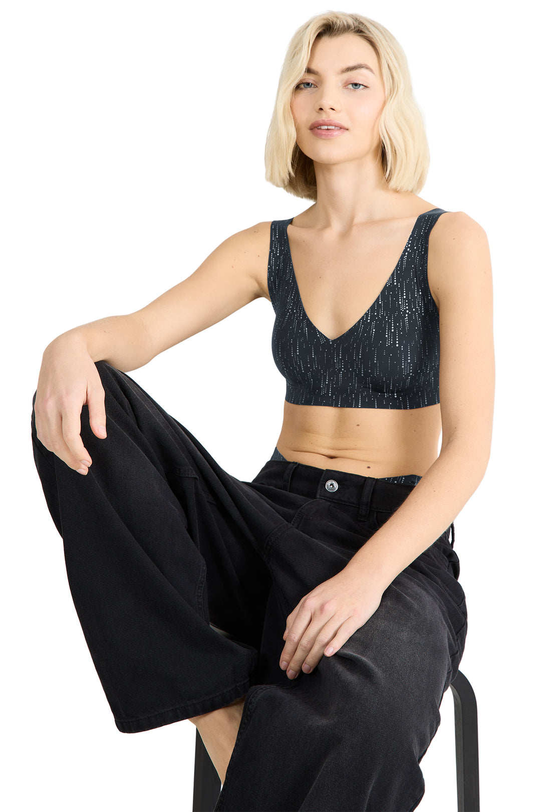 Woman wearing a black bralette and black pants on a white background