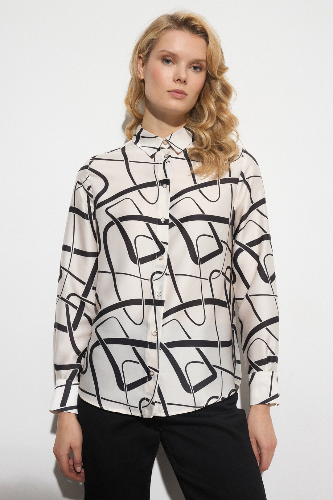 Woman wearing a black and white abstract patterned blouse on a white background