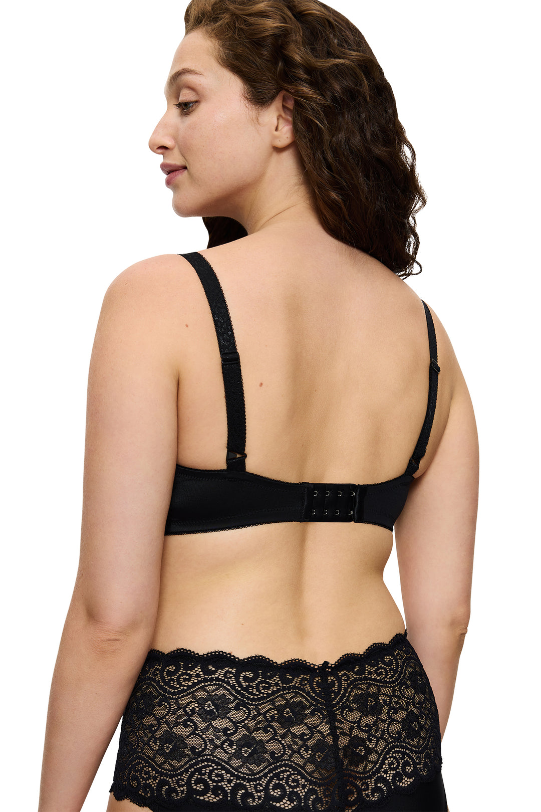 Woman wearing a black lace bra and panties set on a white background