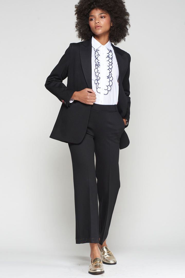Person wearing a black suit with a white shirt featuring a chain design on a plain background