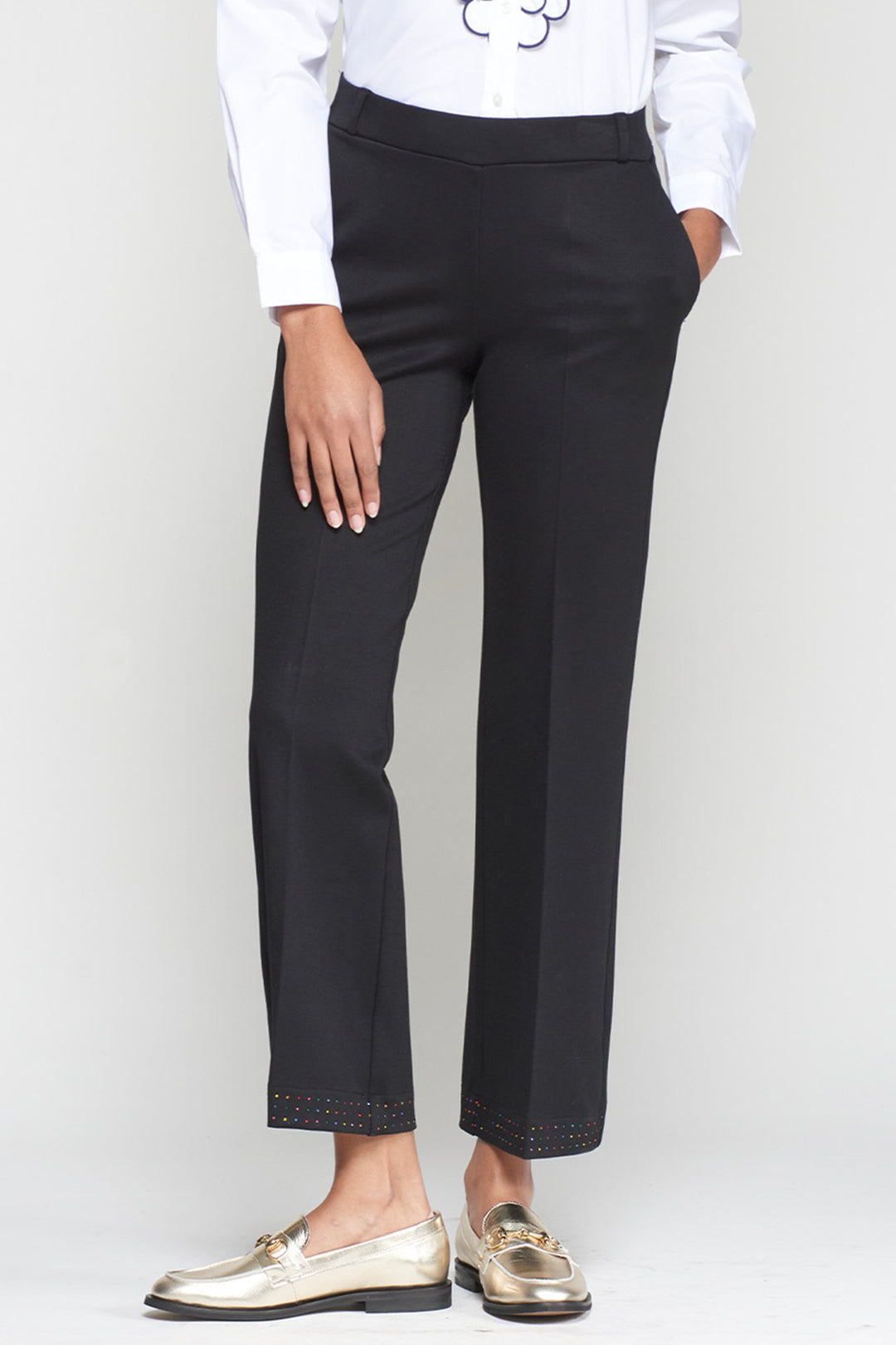 Person wearing black pants and gold shoes on a white background