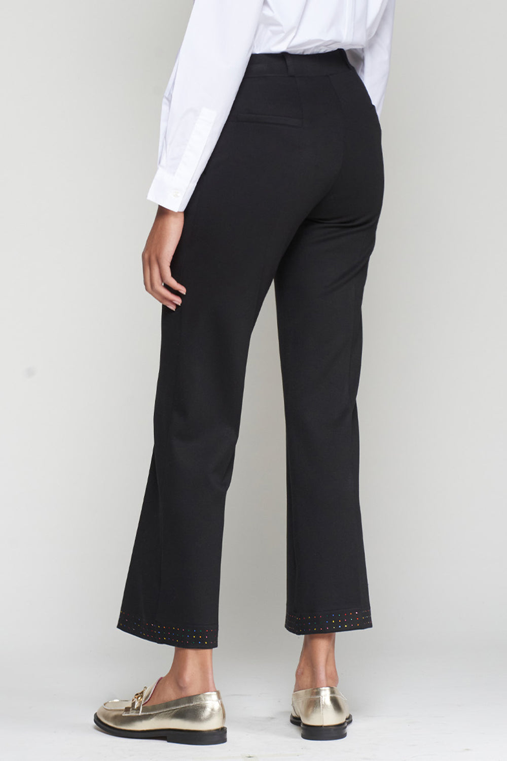 Person wearing black pants and a white shirt on a plain background
