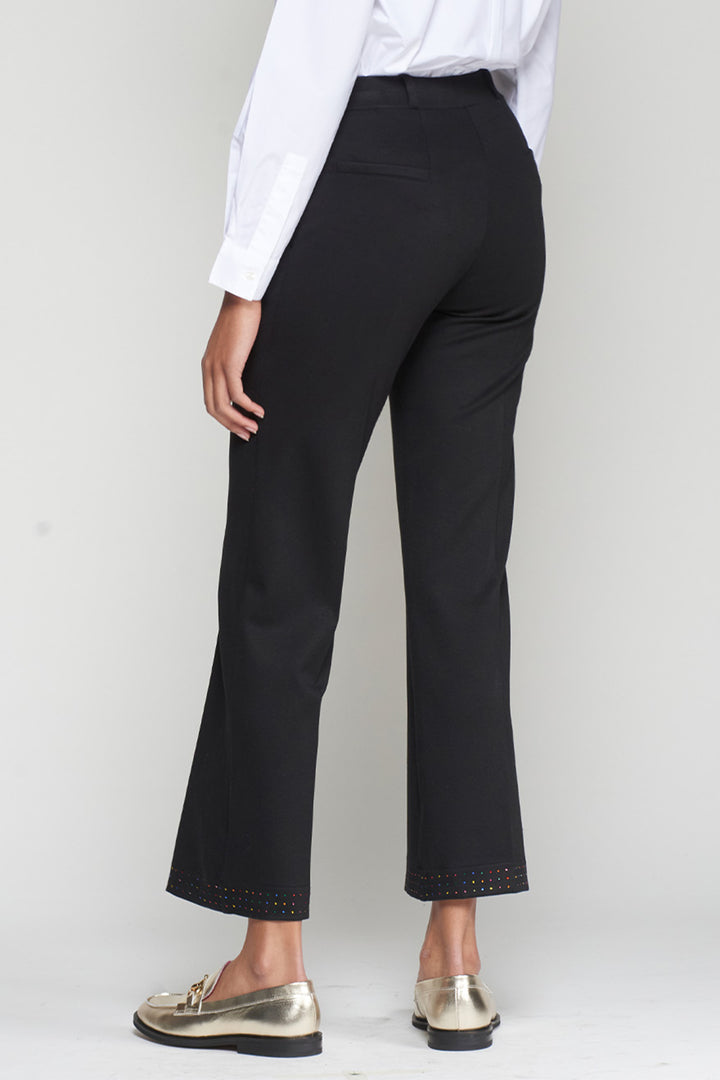 Person wearing black pants and a white shirt on a plain background