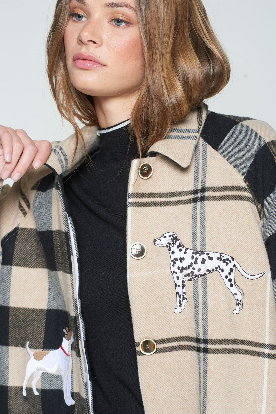 Person wearing a plaid coat with dog illustrations on buttons