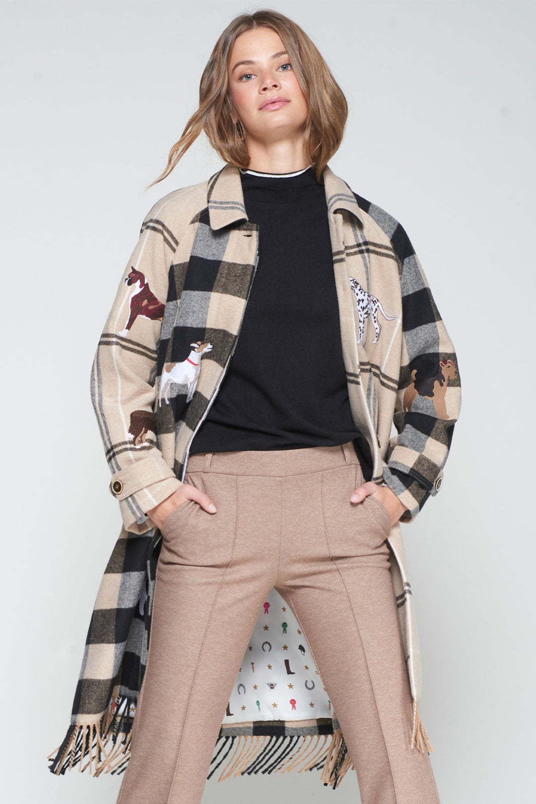 Person wearing a long plaid coat with animal prints on a plain background