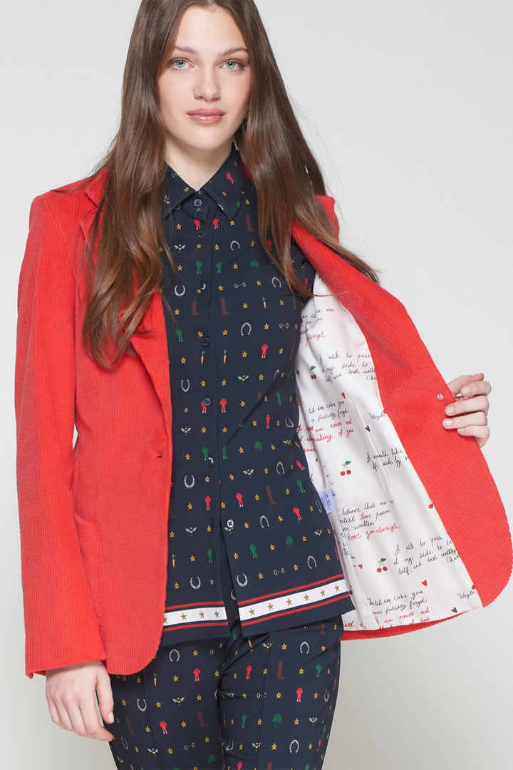 Woman wearing a red blazer over a patterned outfit with a white background