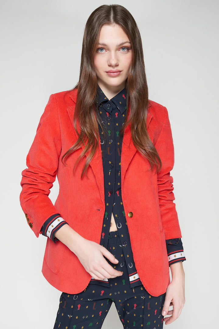 Woman wearing a red blazer over a patterned shirt and pants on a white background