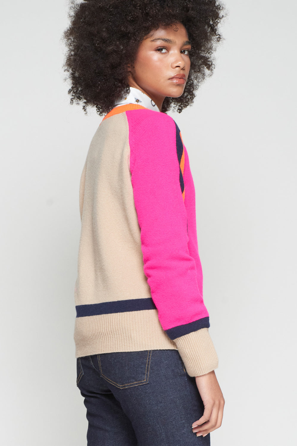 Person wearing a colorful sweater with pink sleeves on a plain background