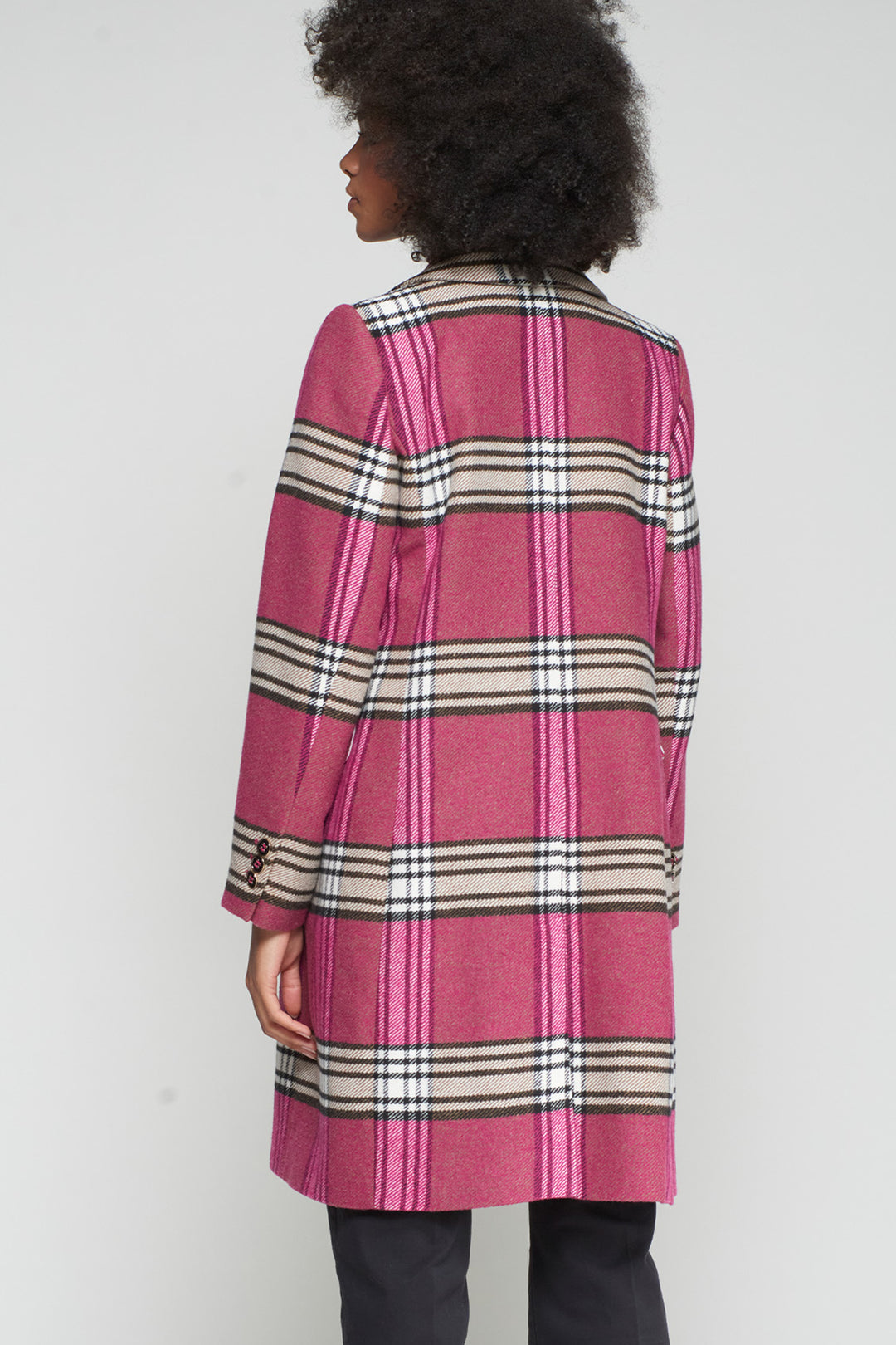Person wearing a pink plaid coat with a white background