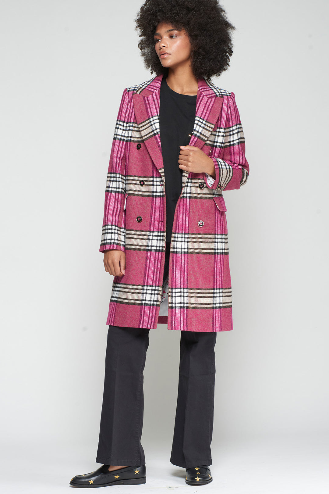 Person wearing a pink and black checkered coat on a white background