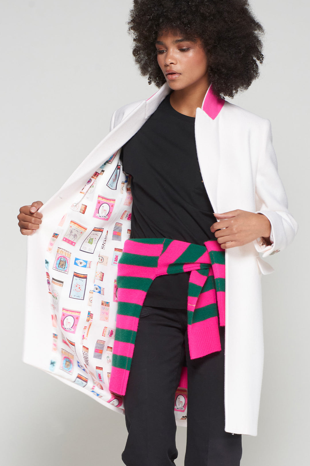 Person wearing a white coat over a colorful patterned garment with a plain background