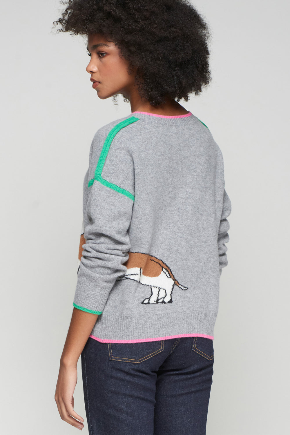 Person wearing a gray sweater with a cartoon dog design on a plain background