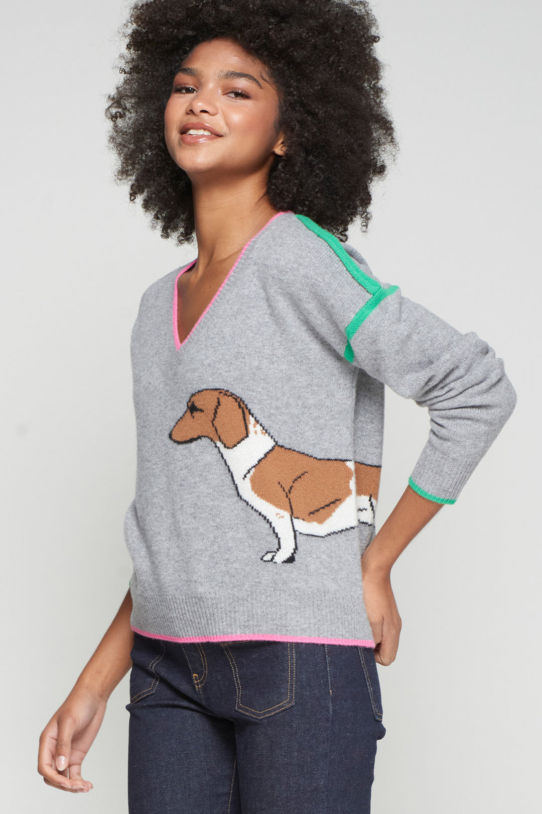 Woman wearing a gray sweater with a dog design on a plain background