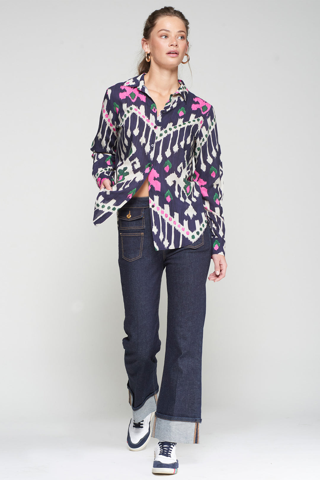 Person wearing a patterned shirt and jeans on a white background