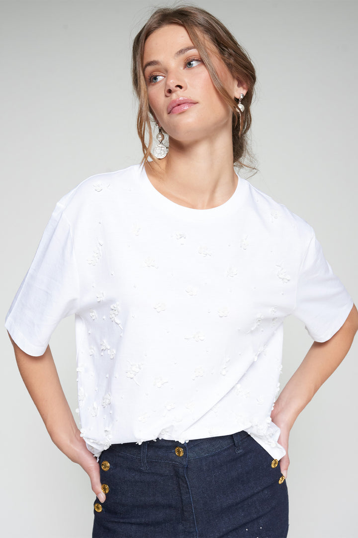 Woman wearing a white t-shirt and dark jeans against a plain background