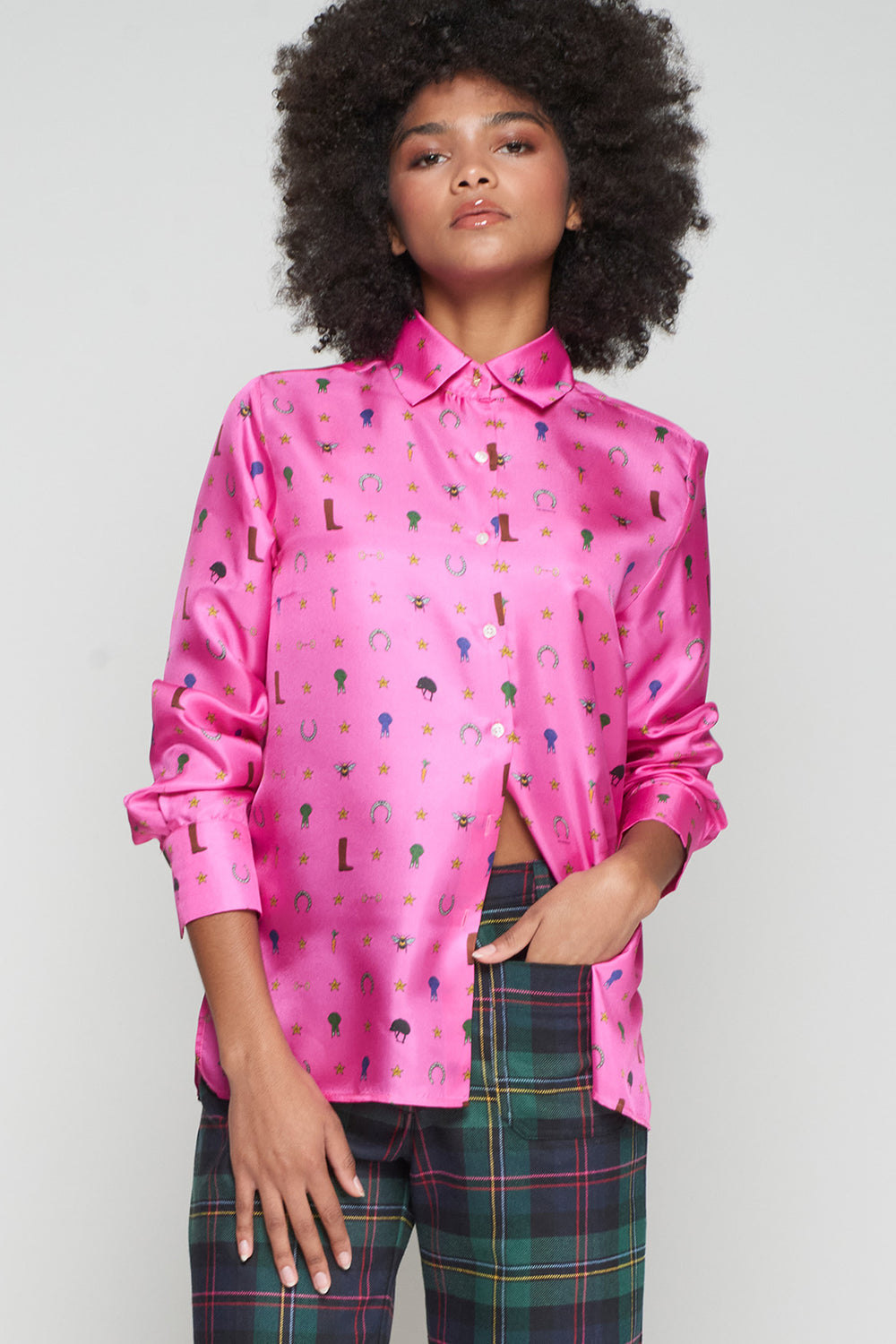 Person wearing a pink patterned shirt with plaid pants on a plain background