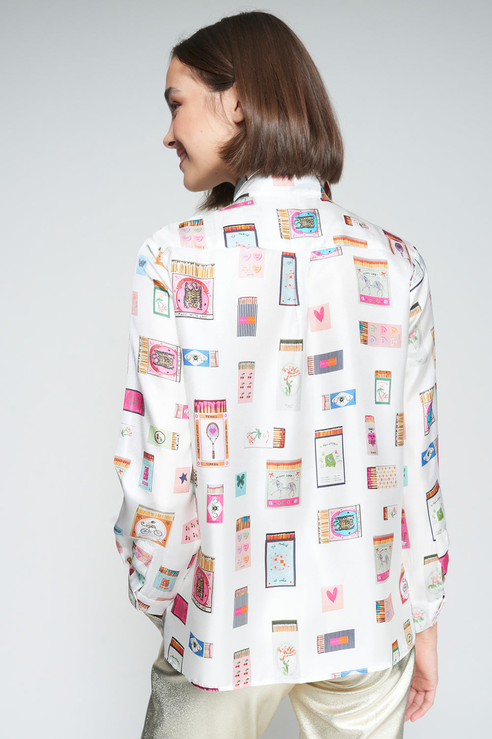 Person wearing a white shirt with colorful pattern on a plain background