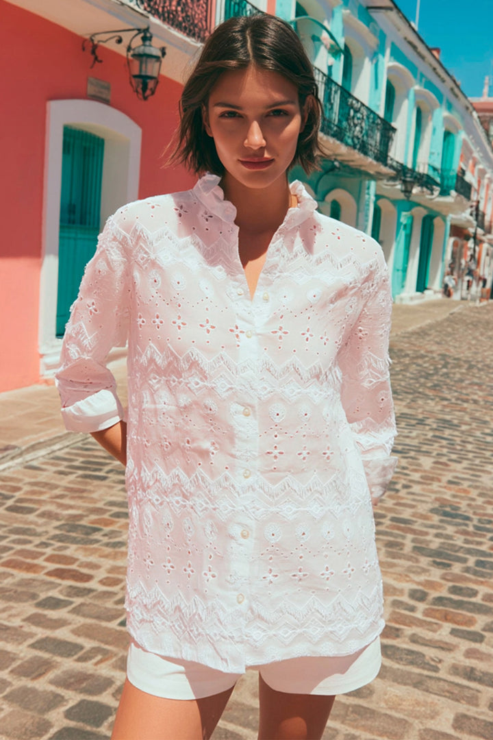 Woman wearing a white lace dress standing on a colorful street.