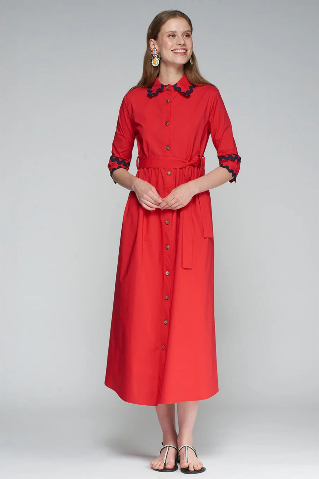 Woman wearing a red dress with black trim on a gray background