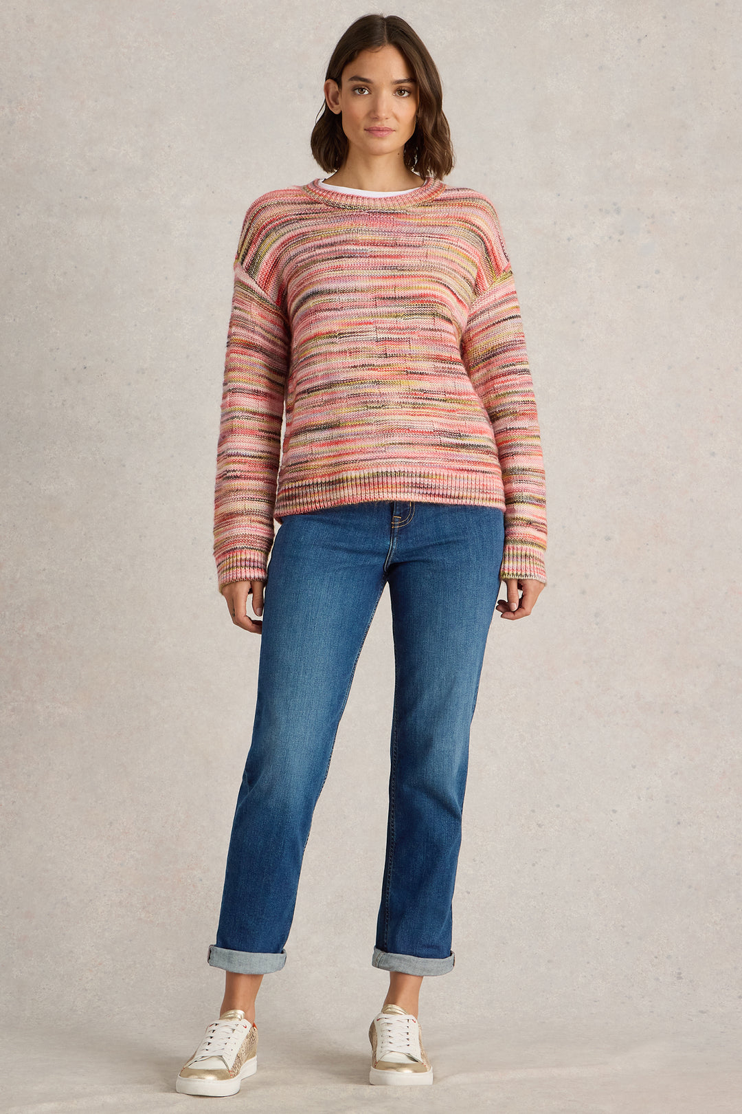 Woman wearing a striped sweater and blue jeans on a beige background