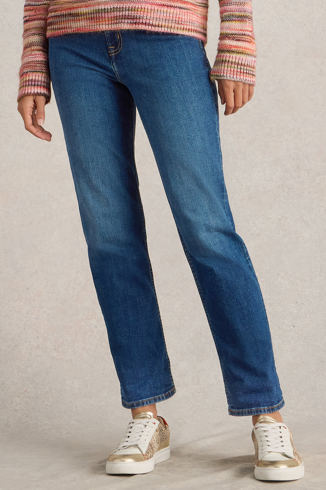 Person wearing blue jeans and a striped sweater on a plain background
