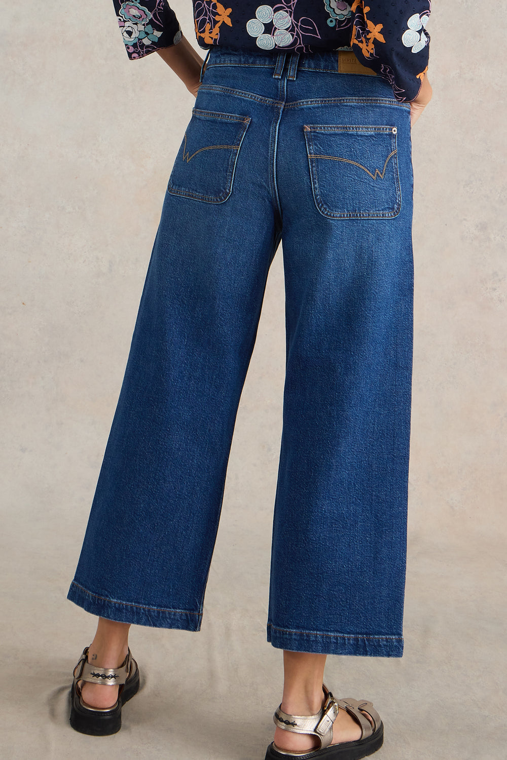 Person wearing blue jeans on a plain background