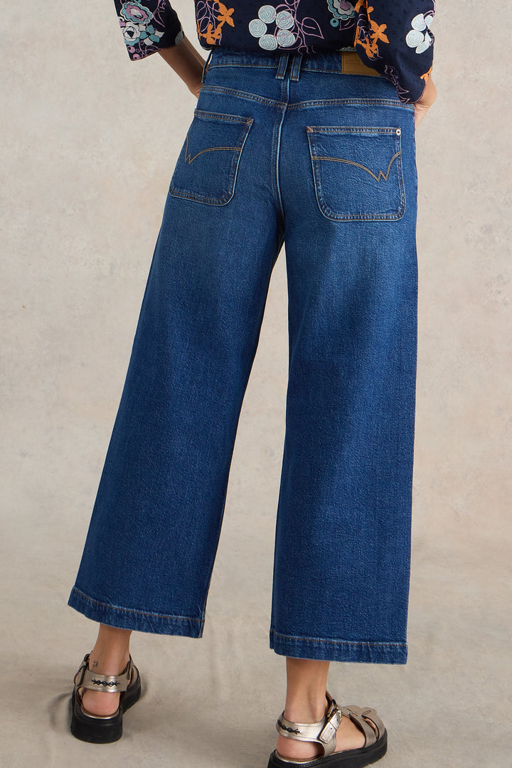 Person wearing blue jeans on a plain background