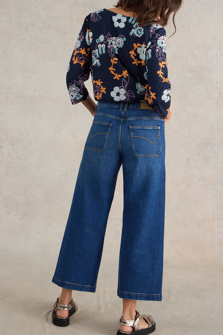 Person wearing a floral top and blue jeans on a plain background