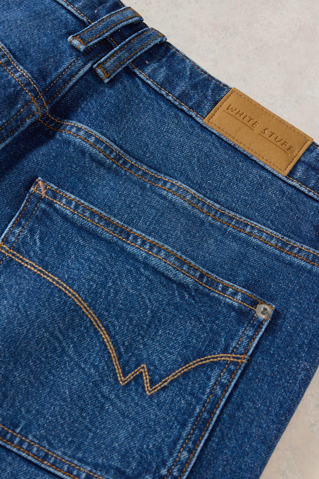 Close-up of blue jeans with a brand label on a light background