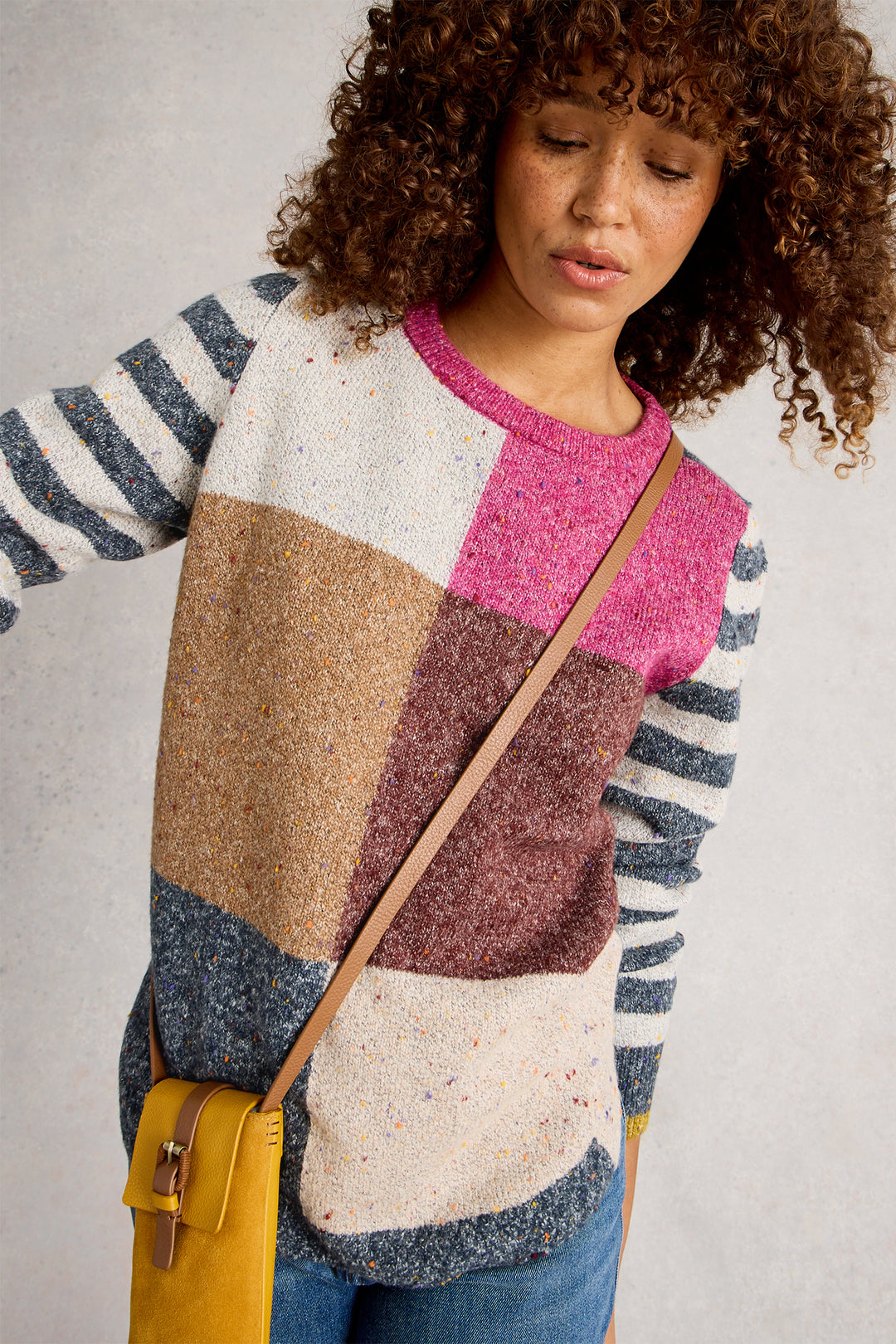 Person wearing a colorful patterned sweater with a neutral background