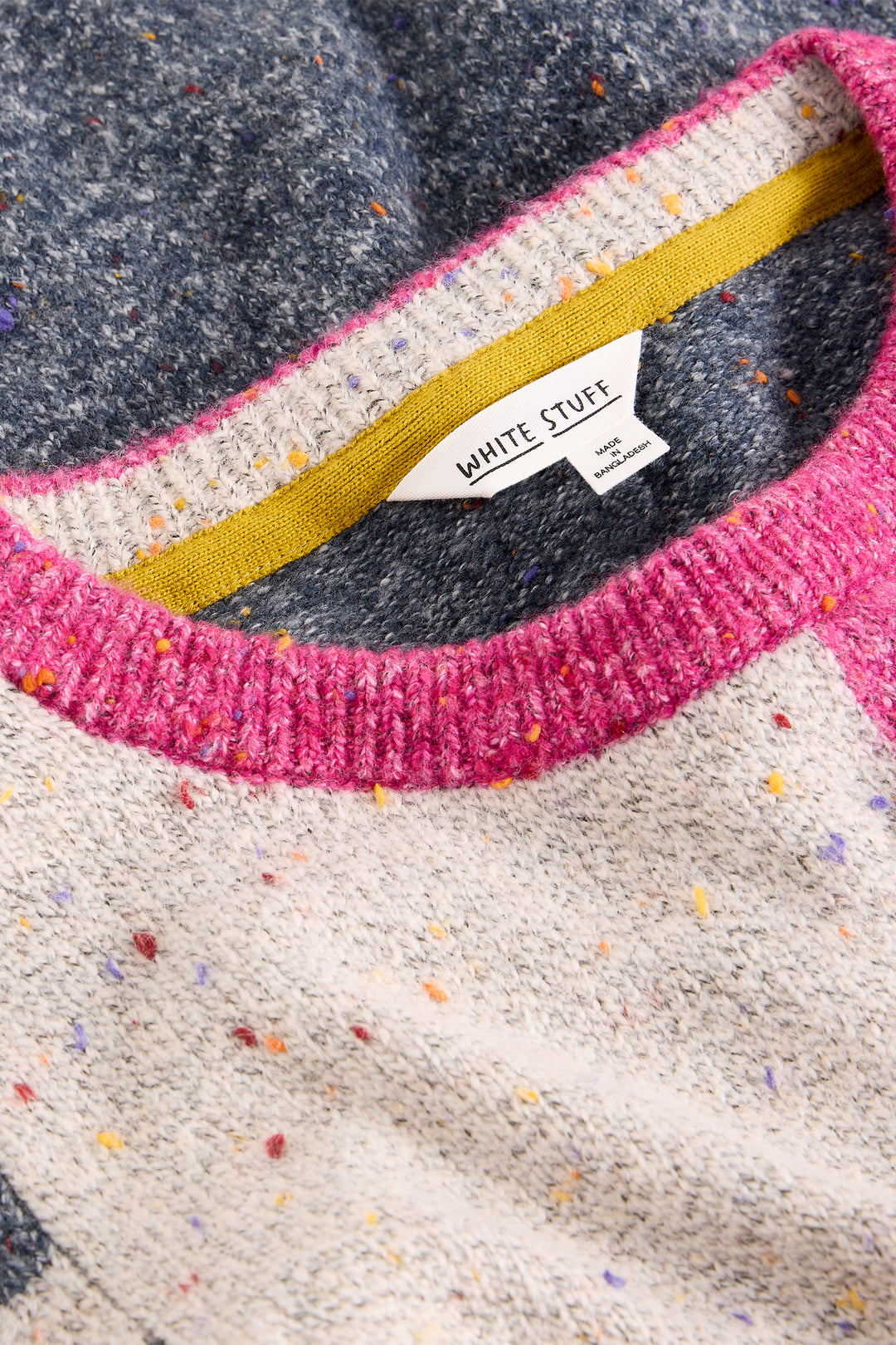 Close-up of a sweater with colorful speckles and a visible brand label.