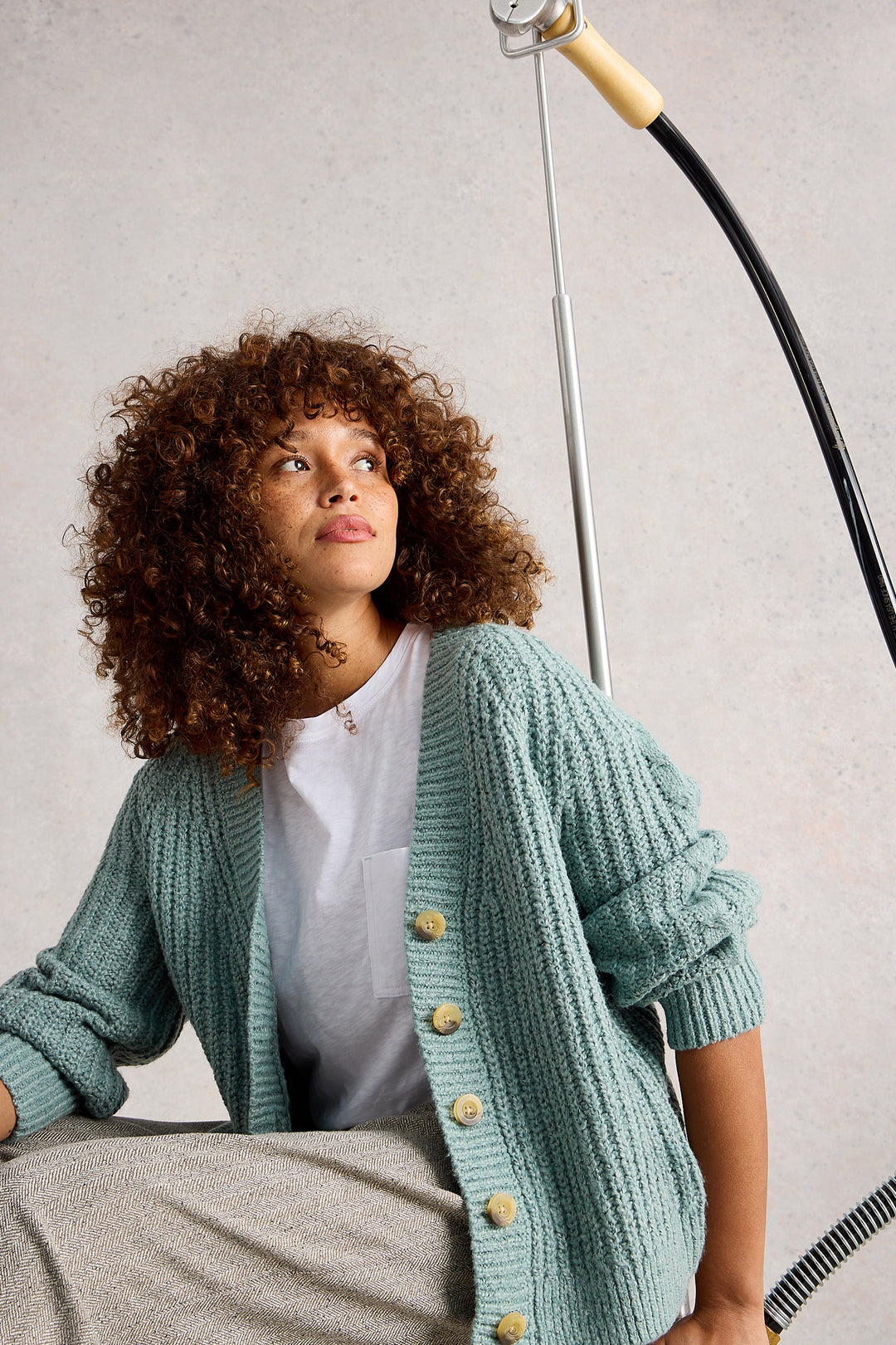 Woman wearing a light blue cardigan with buttons, sitting against a neutral background.