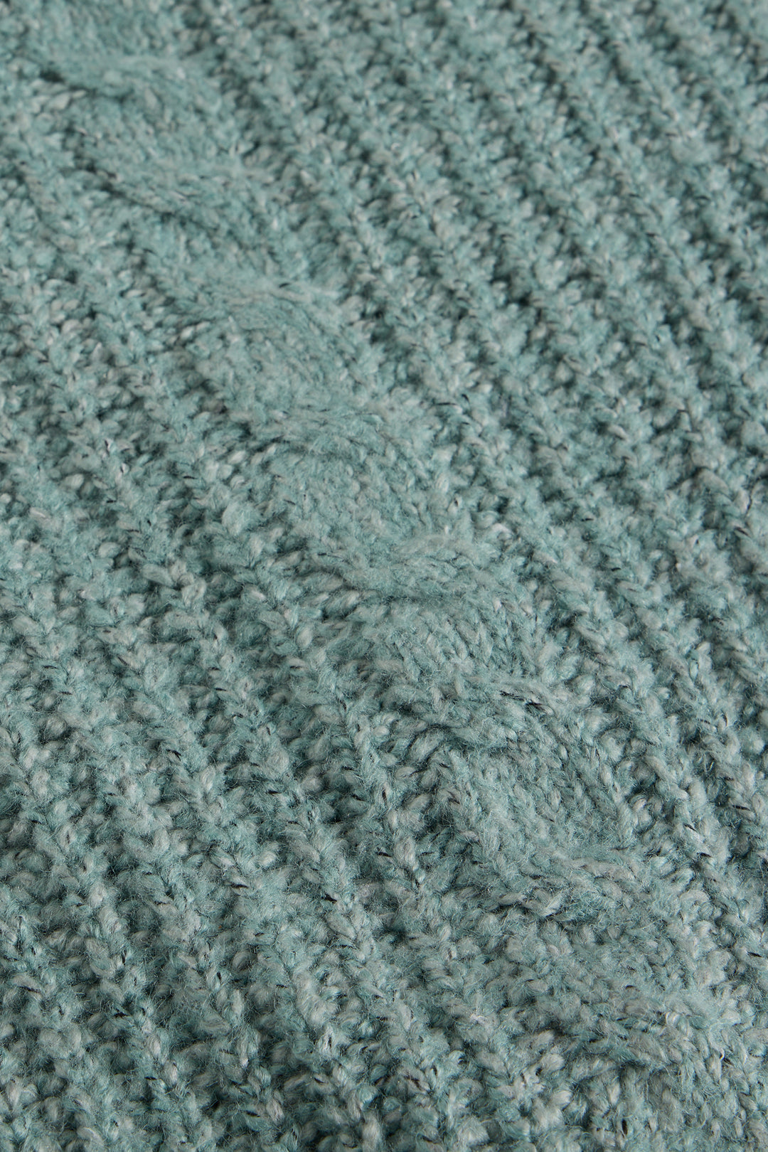 Close-up of a textured teal fabric with a cable knit pattern