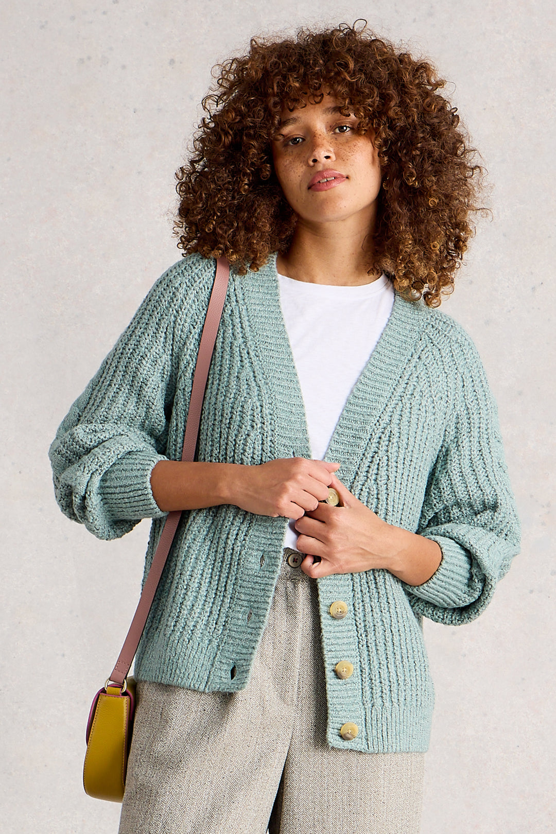 Woman wearing a light blue knitted cardigan with a plain background