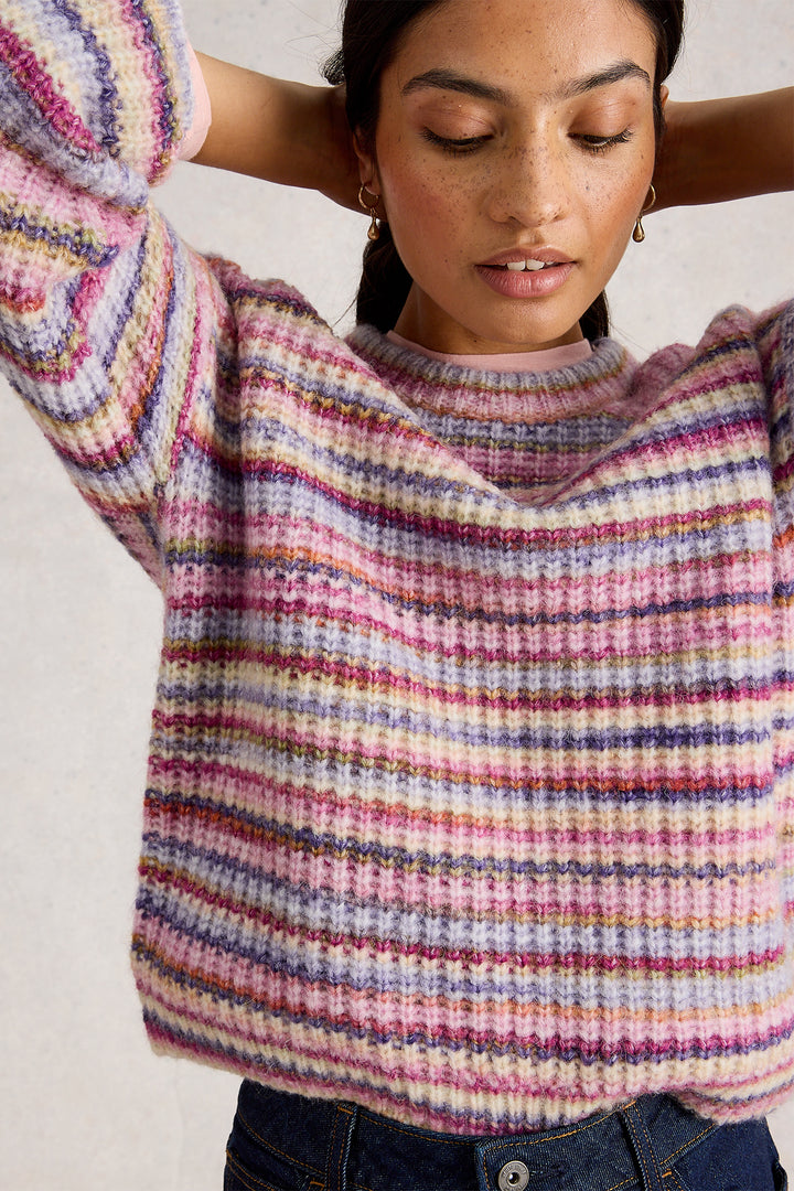 Woman wearing a colorful striped sweater against a plain background