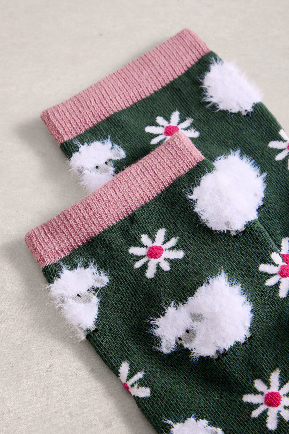 Green socks with white sheep and pink flowers on a beige background