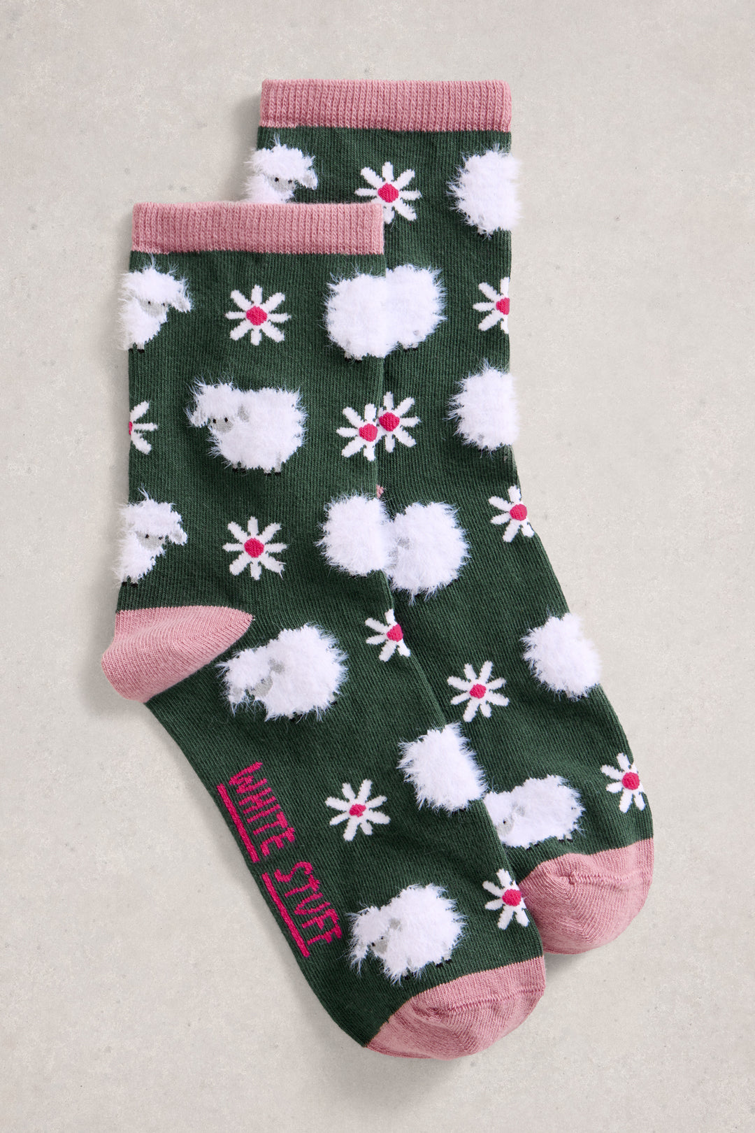 Green socks with white fluffy balls and red flowers on a beige background